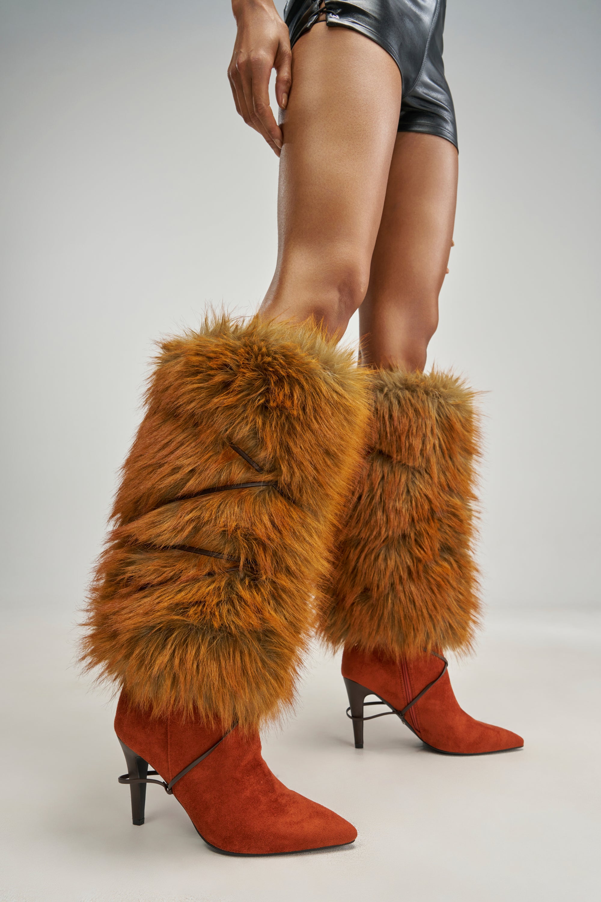 AZALEA WANG FREYDIS RUST FAUX SUEDE AND FUR STILETTO BOOT in a knee-high silhouette with a pointed toe, tall faux fur cuffs, and thin decorative straps.