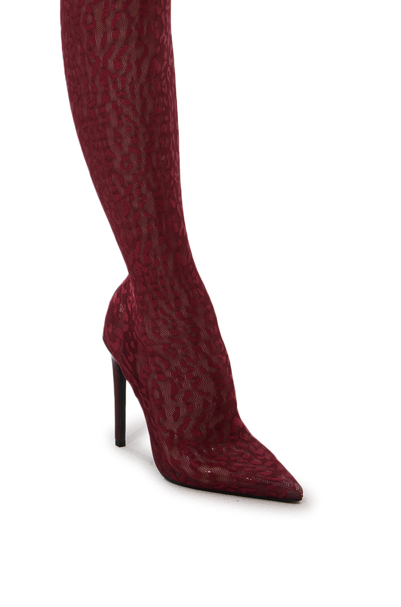 A close-up of a woman’s leg wearing the AZALEA WANG FREJYA Burgundy Leopard Lace Thigh High Boot, featuring a pointed toe and stiletto heel, set against a white background.