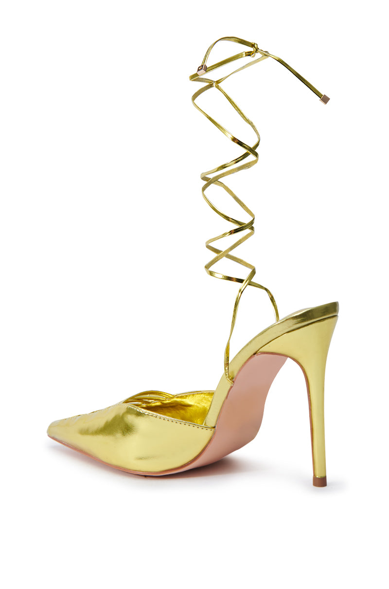 The AZALEA WANG FRIDLI YELLOW LACE UP PUMP showcases a metallic finish, with a pointed toe and long, thin laces that gracefully wrap around the ankle. Its slender stiletto heel is both tall and chic, enhanced by a light pink sole.
