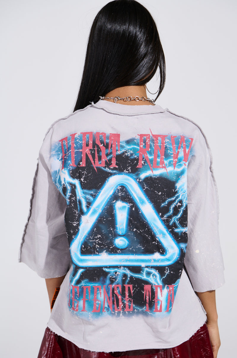 A person with long black hair is seen from behind, wearing the PRIMAL FURY CROPPED GRAPHIC SWEATSHIRT, featuring a neon triangle with an exclamation mark, blue lightning, and red text. They also have a shiny red skirt and a silver necklace.