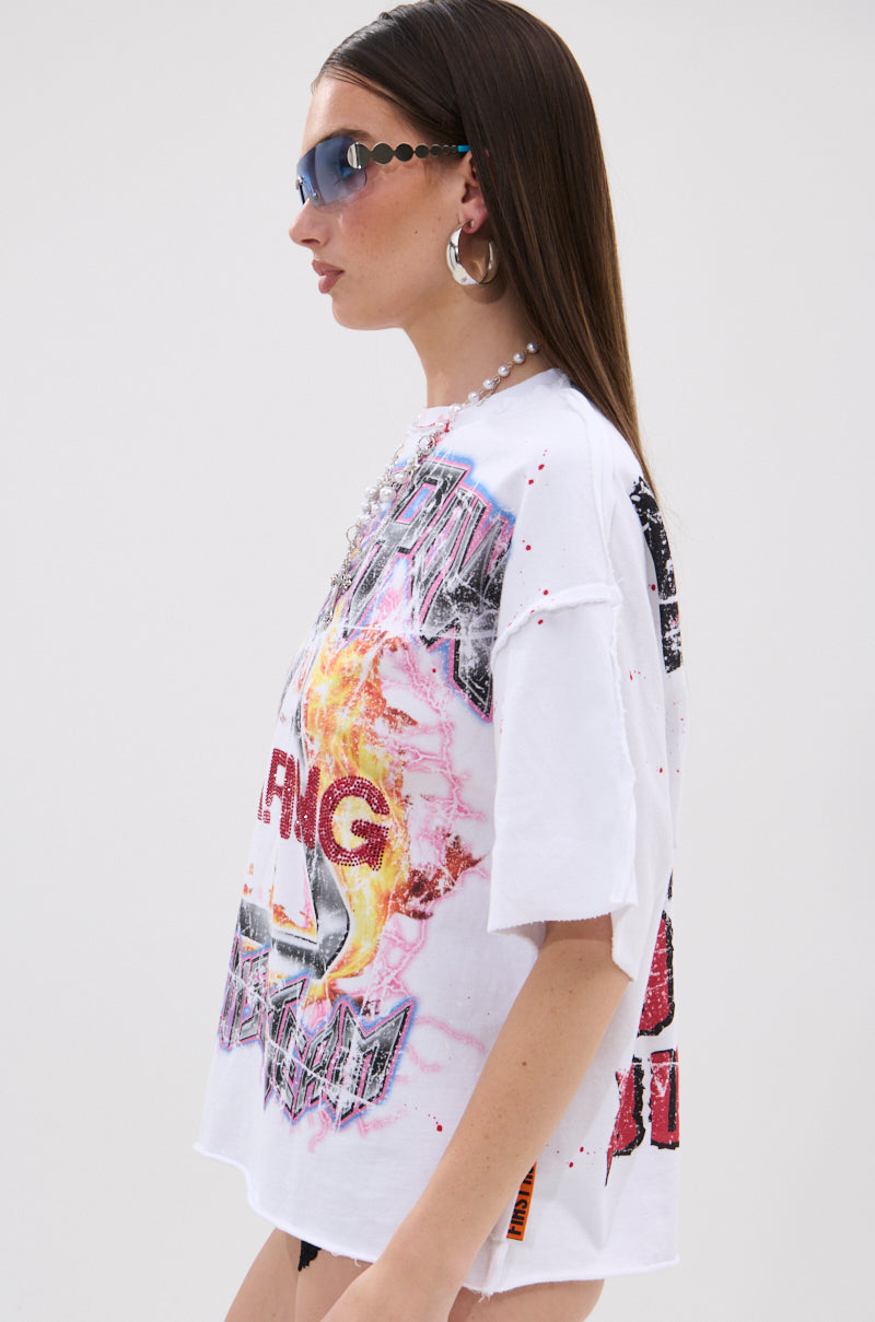 A woman with straight brown hair wears angular blue sunglasses, large hoops, a chunky beaded necklace, and the WARNING SIGNS CROPPED GRAPHIC TEE featuring distressed graphics and an oversized fit.