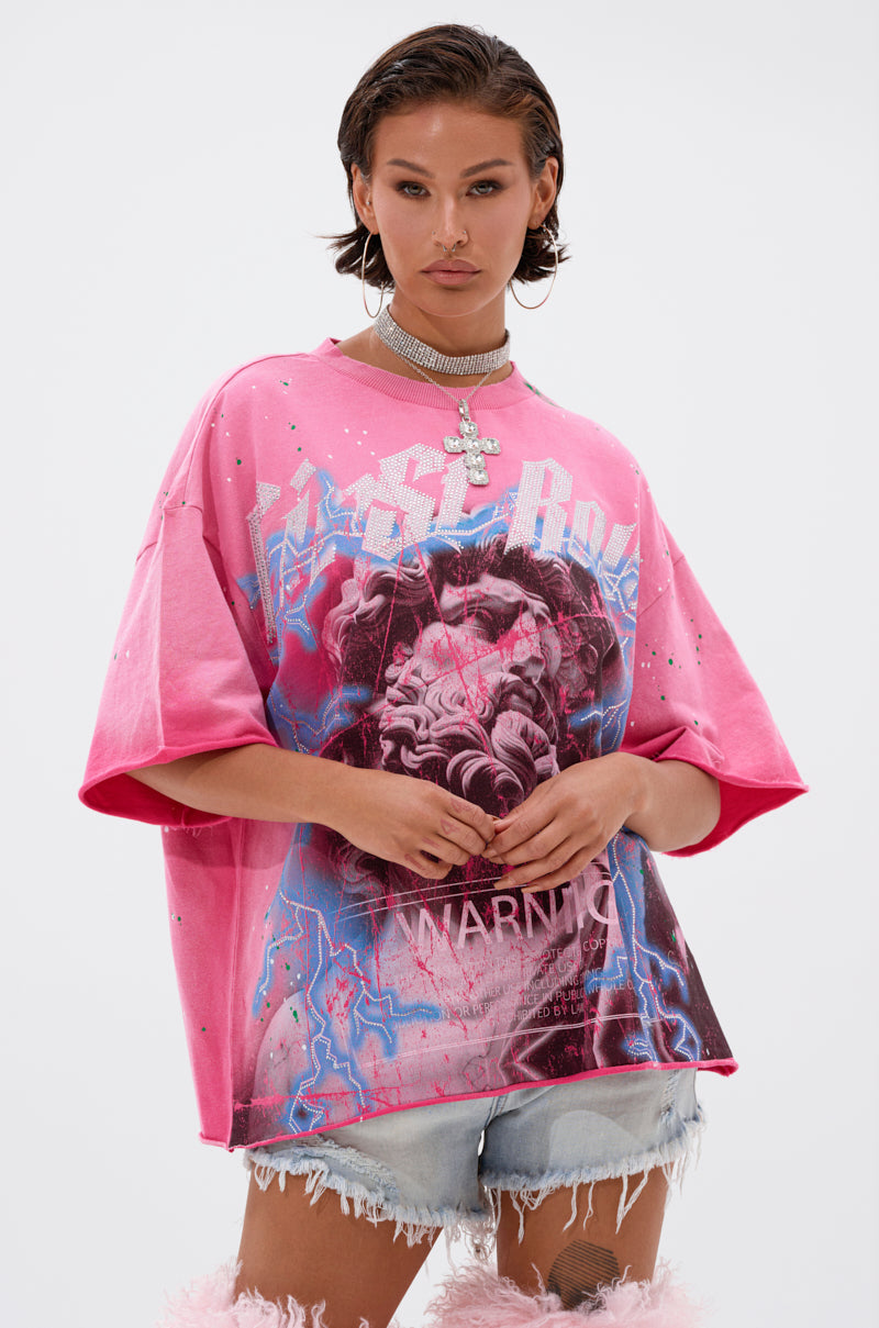 A woman poses against a plain white background wearing the FADE INTO BLACK OVERSIZED TEE with bold designs, light denim shorts, a cross pendant choker necklace, and hoop earrings.