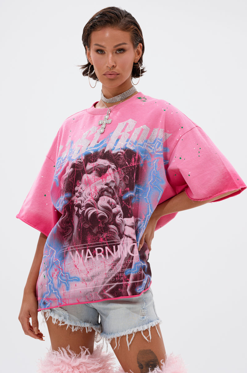 A woman with short, styled hair wears the FADE INTO BLACK OVERSIZED TEE with ripped denim shorts, a chunky necklace, and pink fuzzy leg warmers—serving cool streetwear vibes against a plain white background.