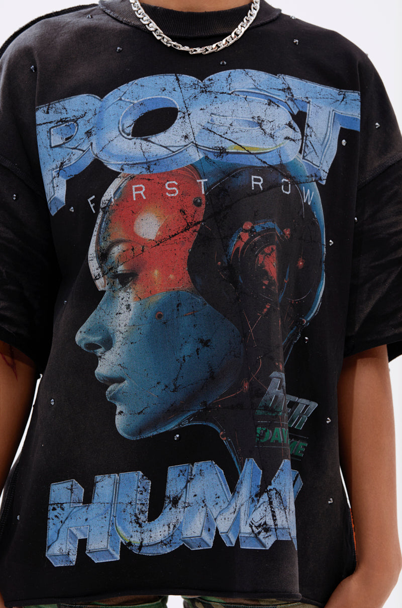 A person wears THE FUTURES CALLING FRENCH TERRY GRAPHIC TEE, an oversized shirt with a blue robotic human head in profile and bold "POST HUMAN" and "FIRST ROW" text, styled with a silver chain necklace.