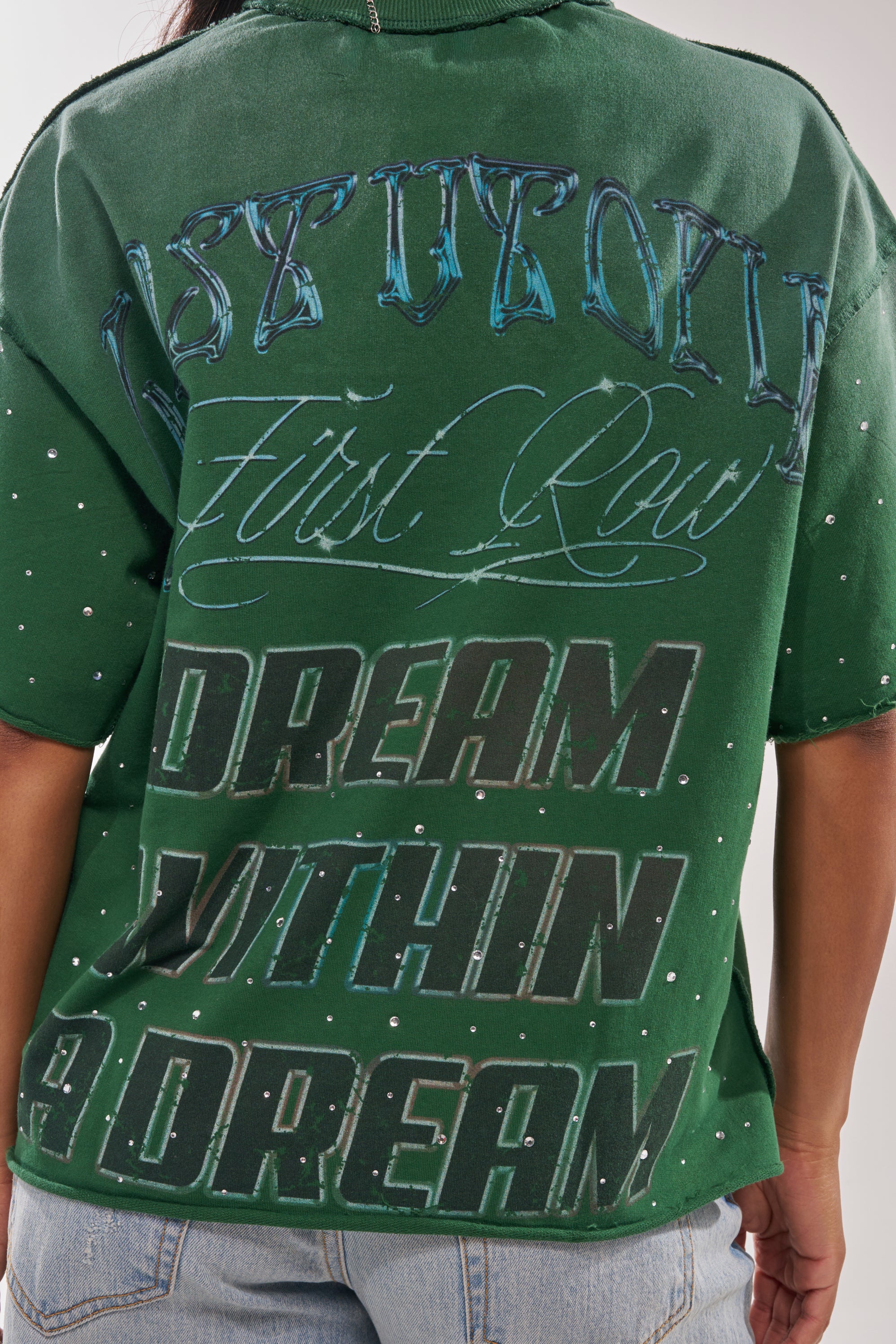 Wearing the FIRST ROW INTERSTELLAR RHINESTONE FRENCH TERRY TEE, an oversized green graphic shirt featuring “First Row” and “DREAM WITHIN A DREAM” in stylized fonts, plus rhinestone accents for standout streetwear style. 6