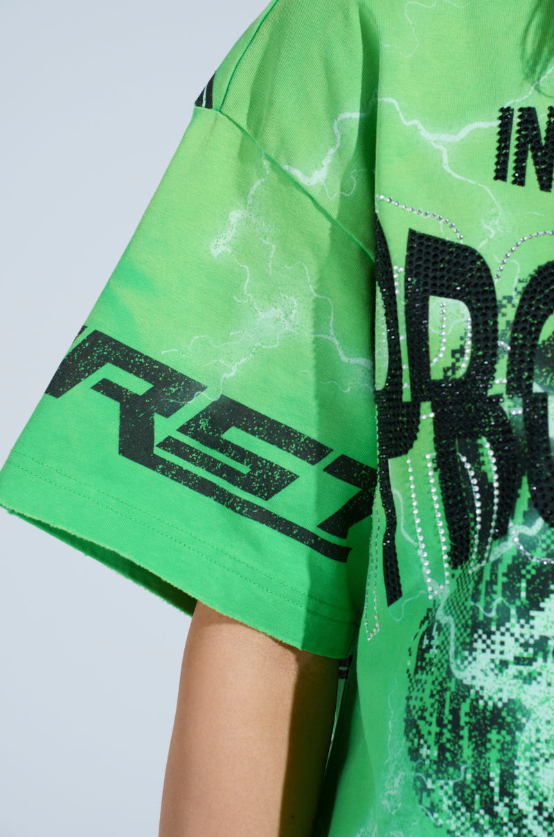 Close-up of a person in the INTELLECTUAL PROPERTY GRAPHIC TEE, featuring an oversized bright green silhouette with eye-catching graphics, abstract black text, and pixel-like designs. The shirt boasts striking lightning patterns against a light blue backdrop.