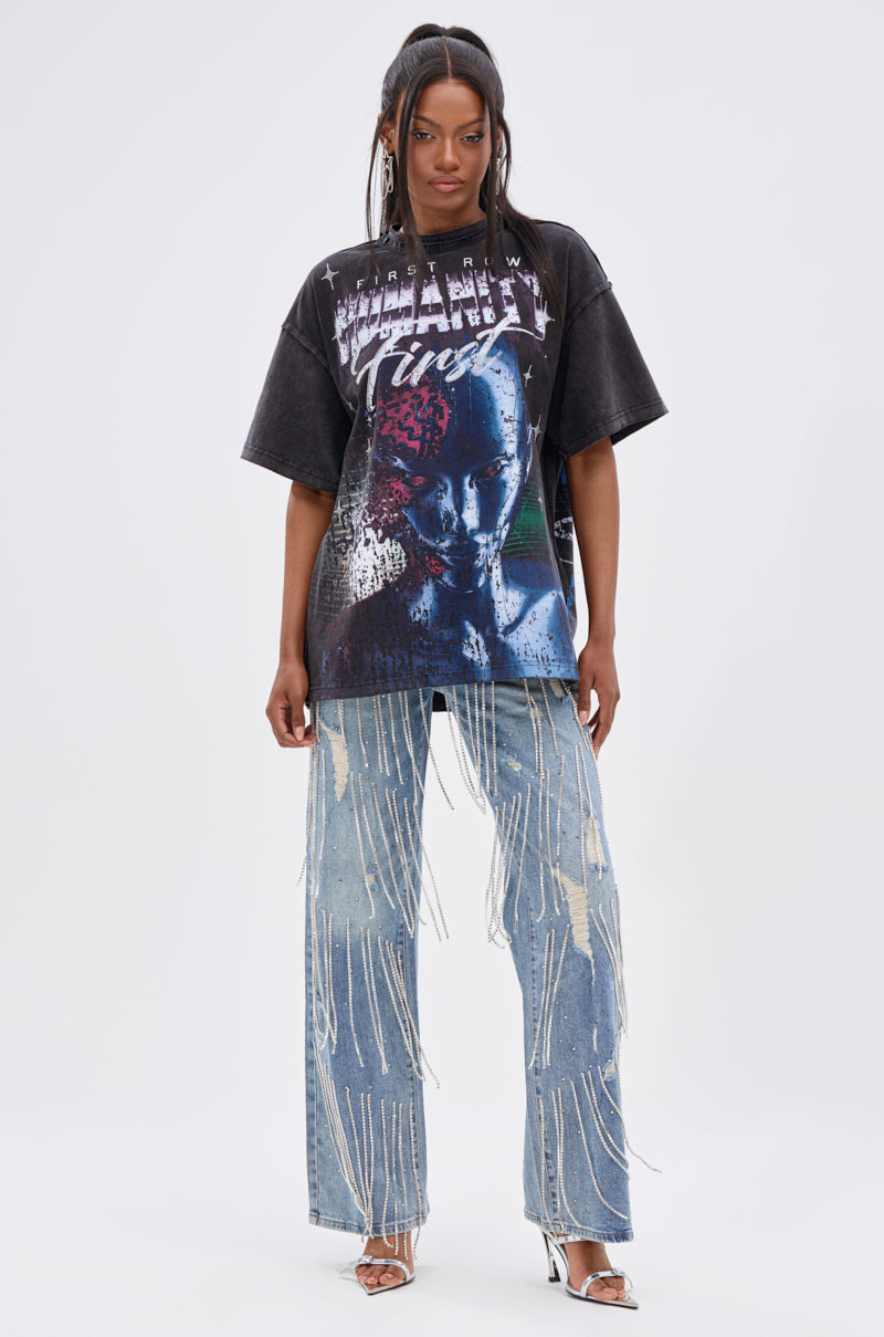 A person stands facing forward on a plain white background wearing the OUT OF BODY OVERSIZED GRAPHIC TEE with a blue and purple streetwear-inspired design, paired with light blue distressed fringe jeans and silver high-heeled sandals. 5