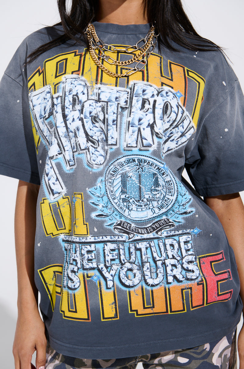 A woman sports an oversized distressed tee, "THE FUTURE IS YOURS," with bold slogans and rhinestone embellishments, enhanced by a chunky gold chain necklace.