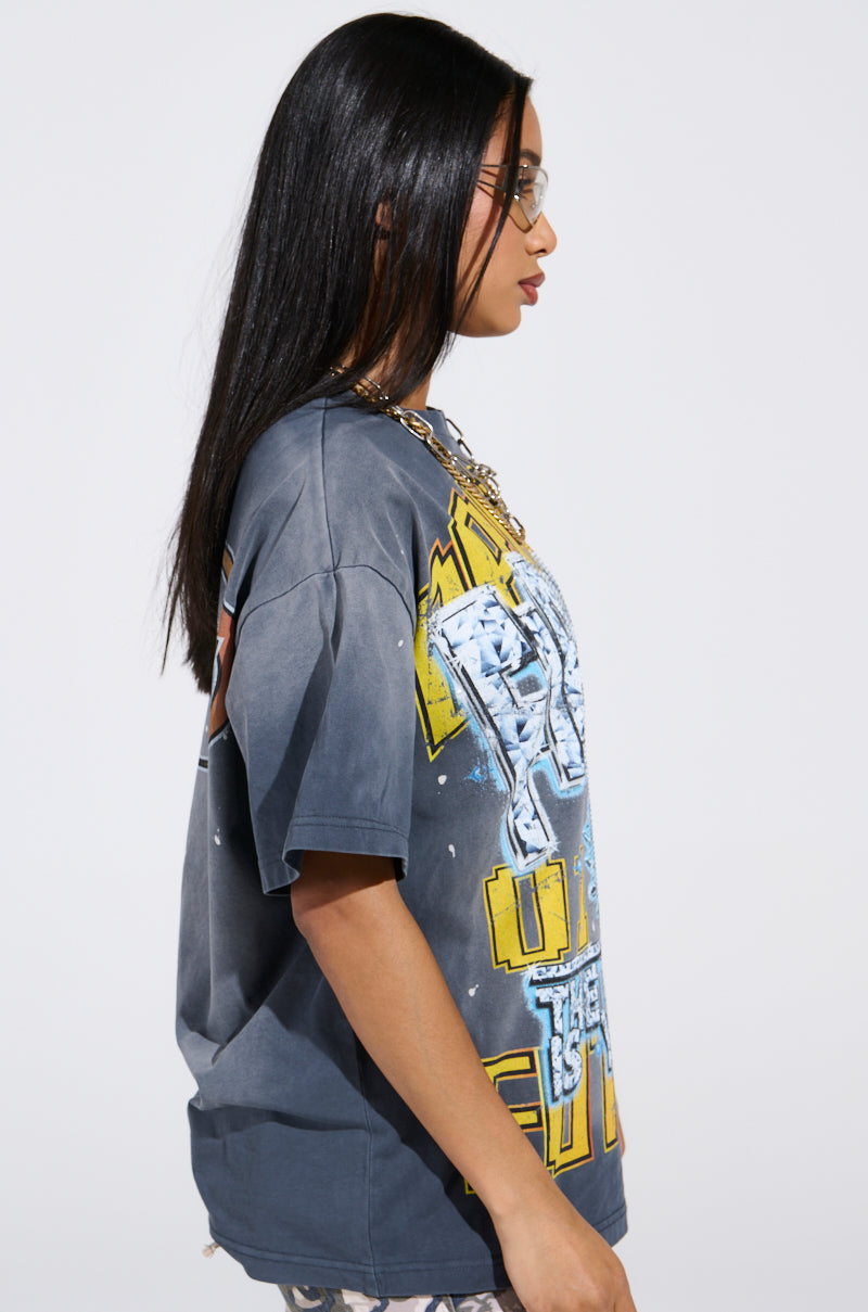 A person with long dark hair and glasses is wearing THE FUTURE IS YOURS OVERSIZED GRAPHIC TEE, featuring rhinestone embellishments. They face sideways against a plain background, looking to the left.