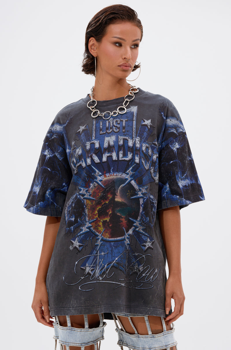 A person wearing the INSANE OVERSIZED TEE featuring a "Lost Paradise" graphic and blue/earth-toned tie-dye marbling, paired with a silver chain necklace and multi-strap pants, stands against a plain white background.