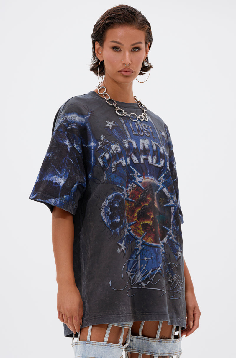A woman with wet-look short hair wears a chunky chain necklace and the INSANE OVERSIZED TEE—an oversized black graphic tee with blue designs and "PARADISE" on it—showcasing edgy style against a plain white background.