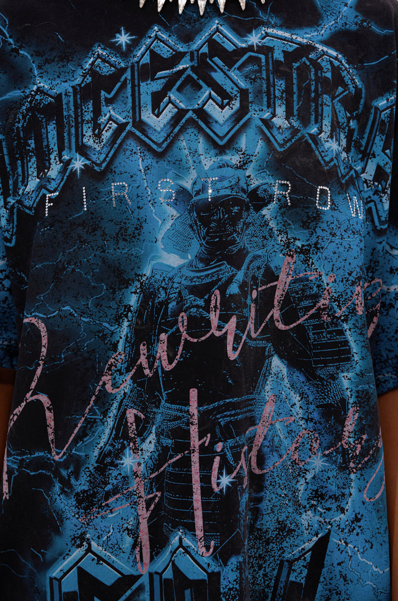 A close-up of the ANCESTRAL FURY OVERSIZED GRAPHIC TEE, featuring a blue base, “ANCESTRAL” at the top, a central robot figure, and bold stylized text like “FIRST ROW” on this relaxed fit statement shirt.
