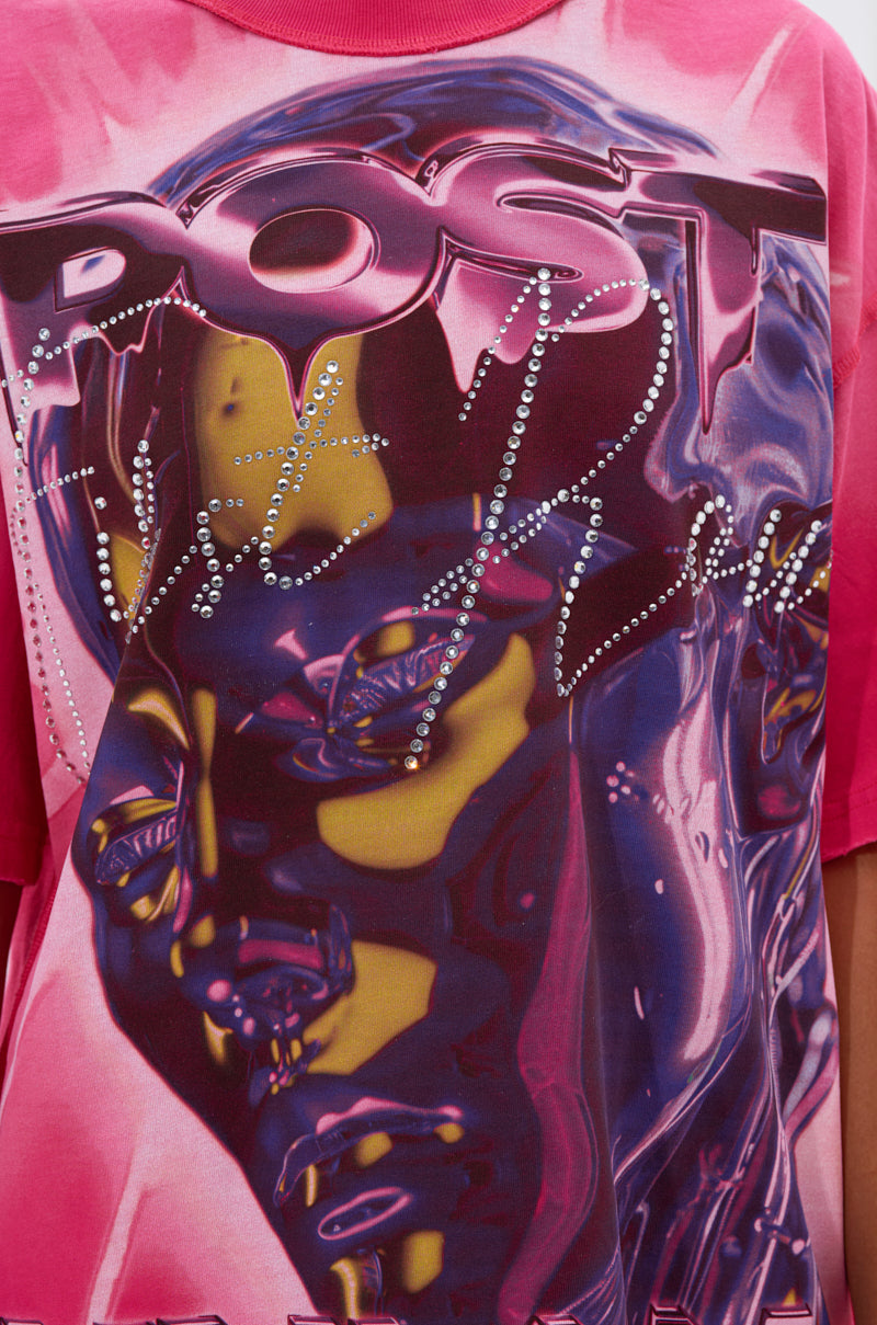 A close-up of the POST HUMAN OVERSIZED GRAPHIC TEE IN PINK, featuring a shiny abstract face design in purple and yellow, "Post" and "Fast Real" stylized lettering, and rhinestone details on this standout streetwear piece.