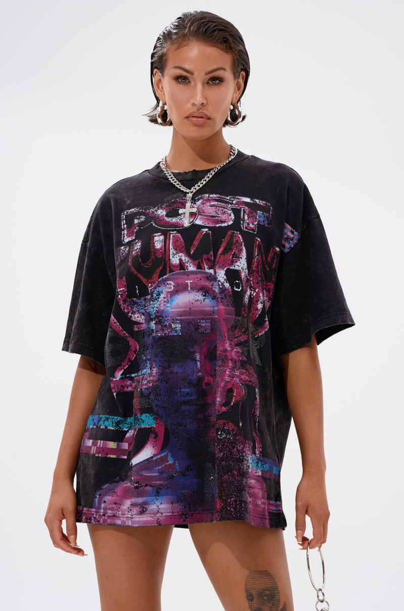 A person with short slicked-back hair and hoop earrings sports a FIRST ROW CYBERTRONICS OVERSIZED GRAPHIC TEE, channeling futuristic streetwear vibes as they stand confidently against a plain light background. 0