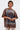 A woman with wet hair models the POST HUMAN OVERSIZED GRAPHIC TEE, a brown streetwear shirt with 
