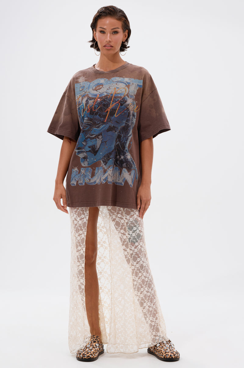 A woman with short dark hair and a neutral expression stands against a white background wearing the POST HUMAN OVERSIZED GRAPHIC TEE, paired with a long sheer lace skirt and leopard print shoes. 4