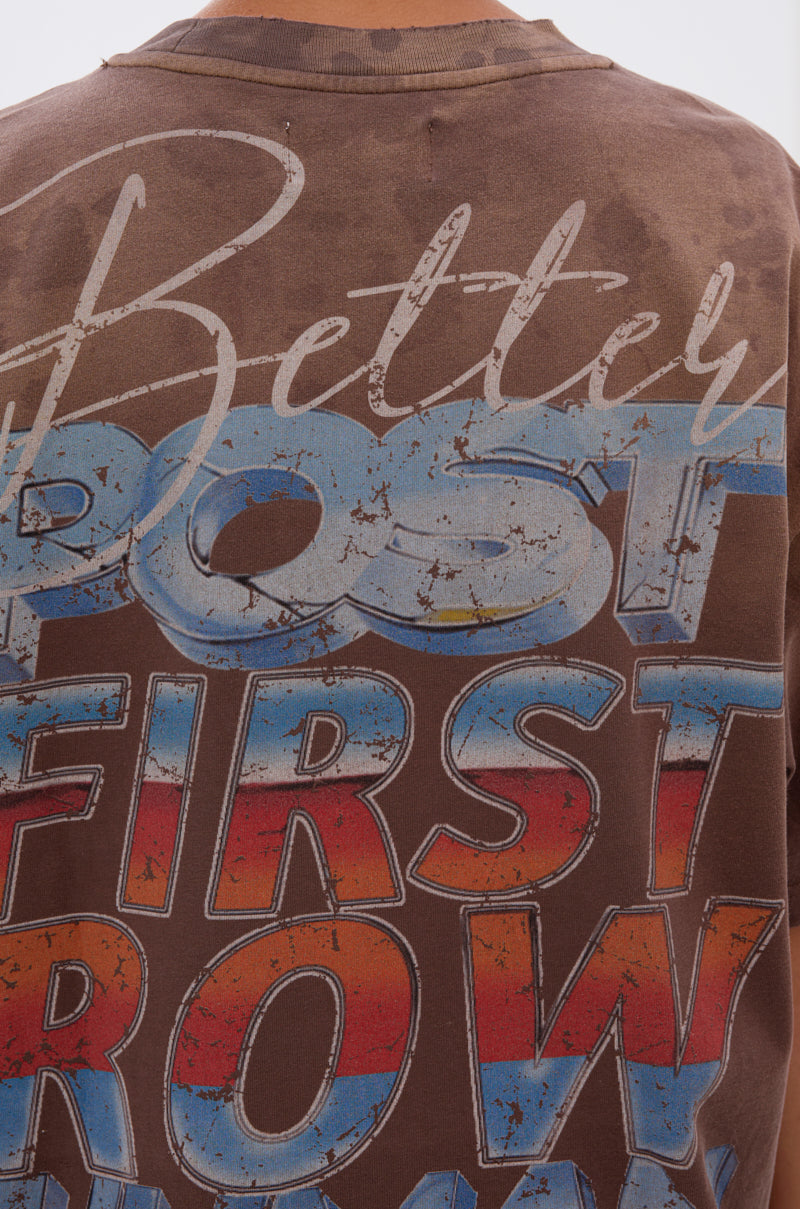 A person wears the POST HUMAN OVERSIZED GRAPHIC TEE, a brown vintage-style shirt featuring large, distressed "Better Post First Row" text in beige, blue, red, and white—a bold statement in cyberpunk streetwear. 5