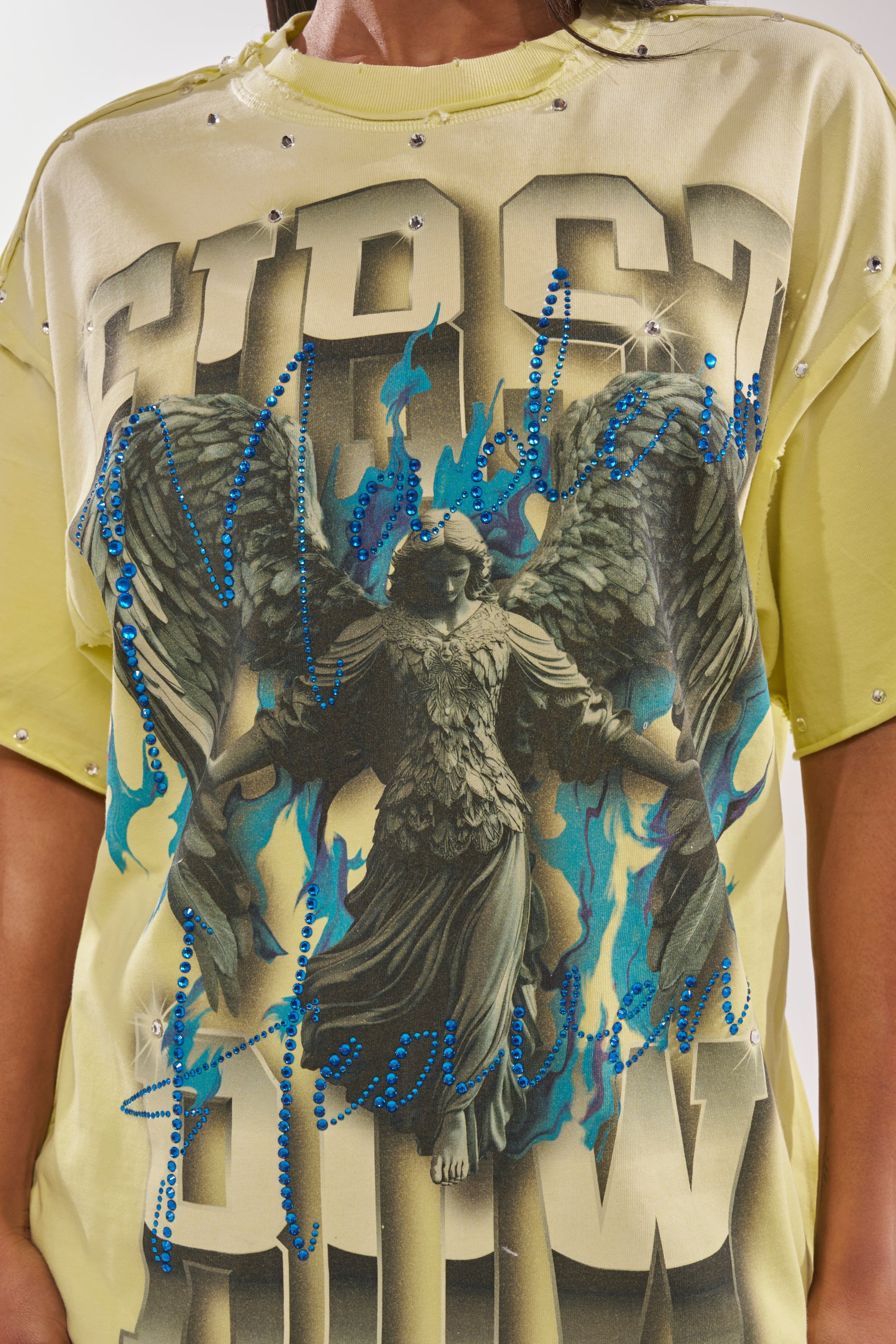 The FIRST ROW NEW RENAISSANCE RHINESTONE TEE showcases a dark-winged angel with blue flames, rhinestone details, and bold metallic text with blue rhinestone accents—ideal for standout streetwear style. 6