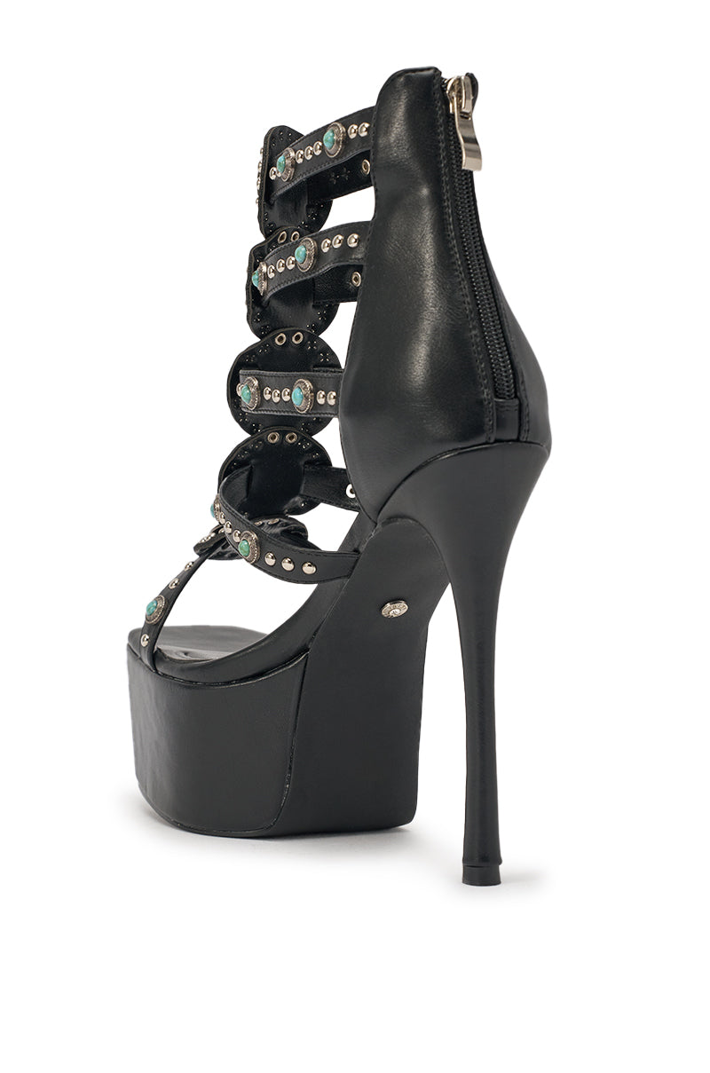 The AKIRA GOLD FUANMARA Black Embellished Sexy Stiletto PU Sandal features a boho-chic platform design with multiple black faux leather straps, silver studs, turquoise gems, a back zipper, and a tall stiletto heel. 5