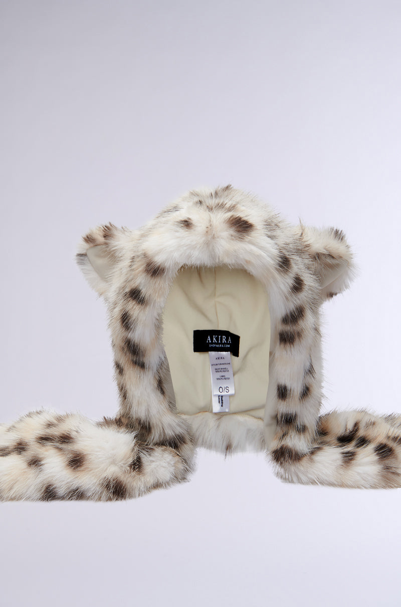 Introducing the Anime Dreamin Faux Fur Hood: a cute, snow leopard-inspired fuzzy hat complete with animal ears and long side flaps. Crafted from cozy faux fur, it features an interior lined with soft fabric and a visible "AKIRA" tag. The hood is elegantly showcased against a plain gray backdrop. 7