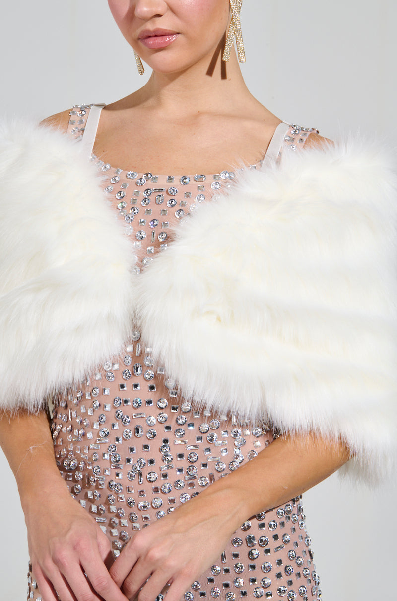 A woman in a sparkling, high-glam gown adorned with sequins and an elegant TO THE GALA FAUX FUR SHAWL draped off her shoulders, wearing dangling earrings. Her face is partially visible, and her hands rest gently on the shawl. 7