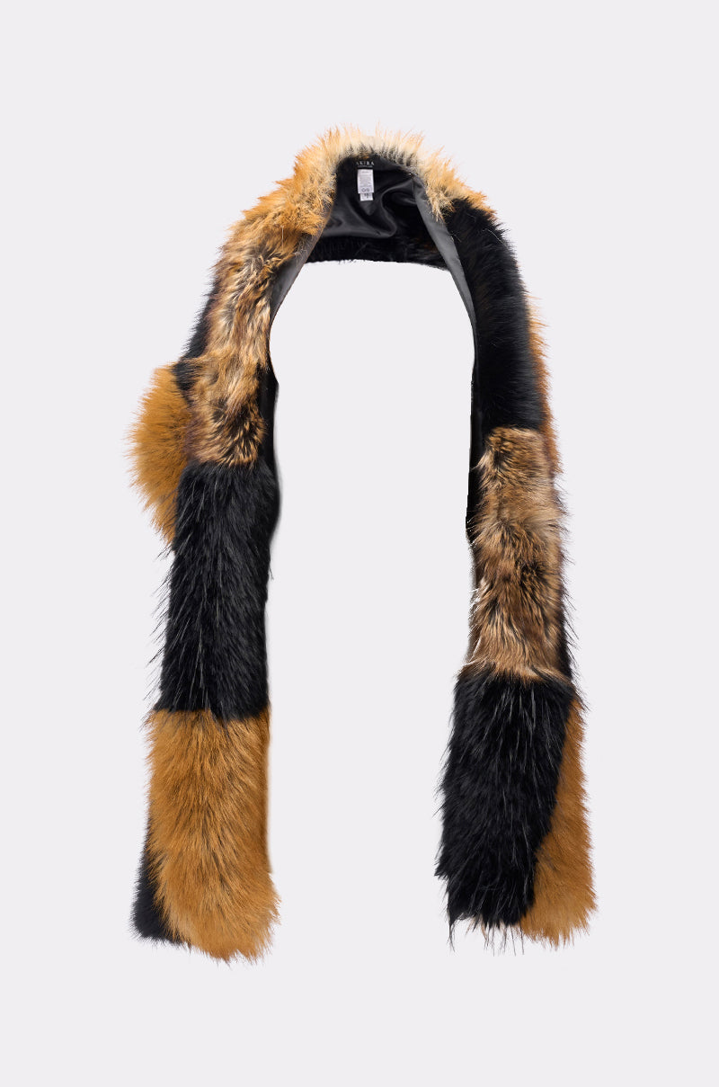 The COSMO FAUX FUR SCARF is a long, rectangular oversized scarf featuring a patchwork design in black, brown, and tan, shown on a plain light gray background. 3