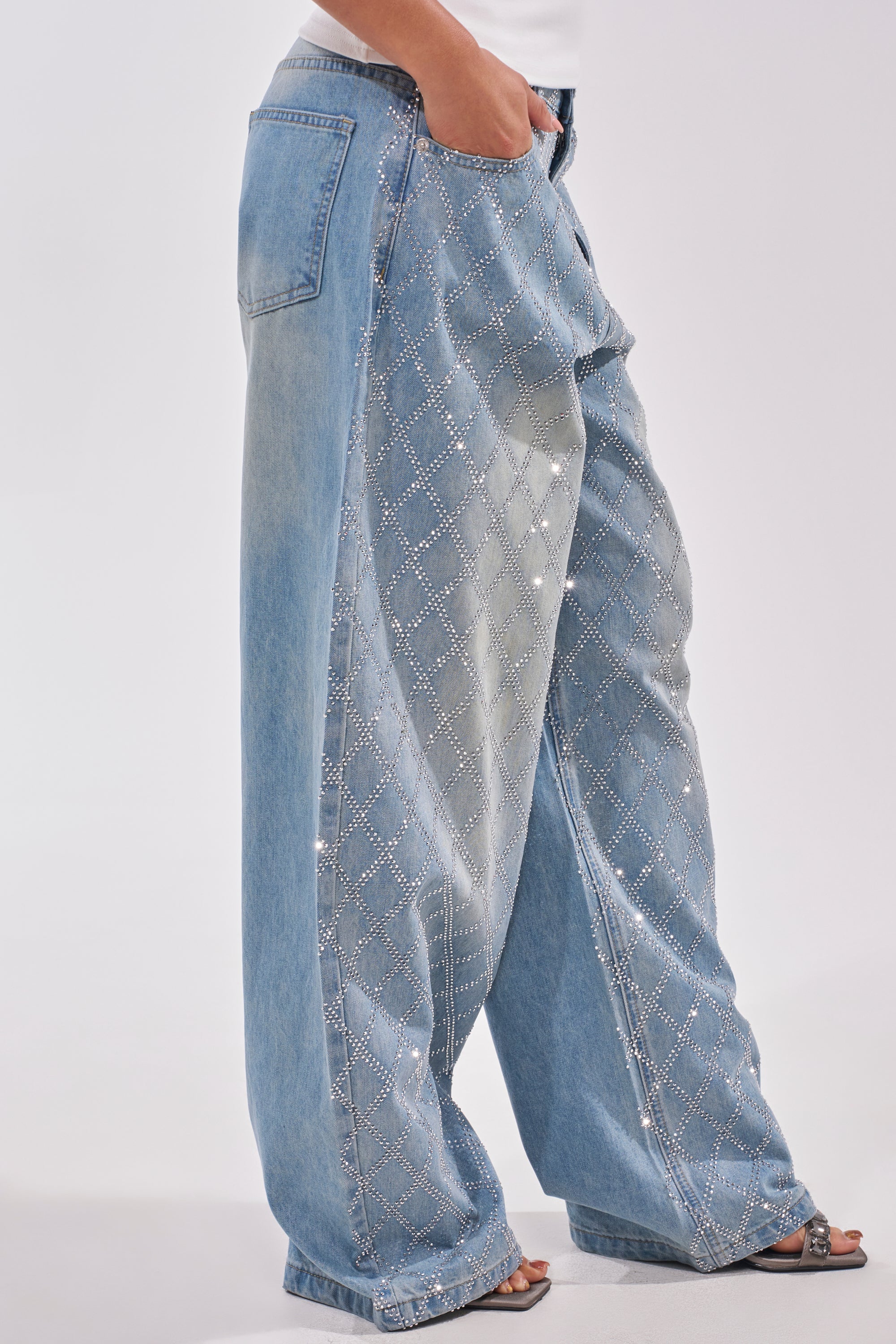 Wearing SHINE BRIGHT RHINESTONE DENIM high-rise wide-leg jeans with a diamond rhinestone lattice, a person pairs them with a white top and open-toe sandals, partly visible against a plain light background. 2