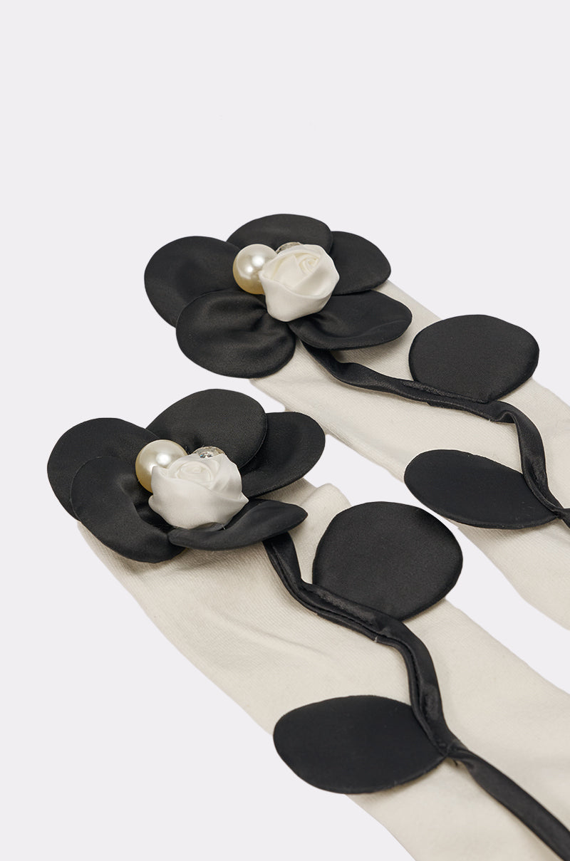 FLOWER POWER APPLIQUE SOCKS feature elegant black satin floral appliqués, each with a white rose and pearl accent at the center—an exquisite touch that perfectly complements sheer white gloves with matching floral details. 3