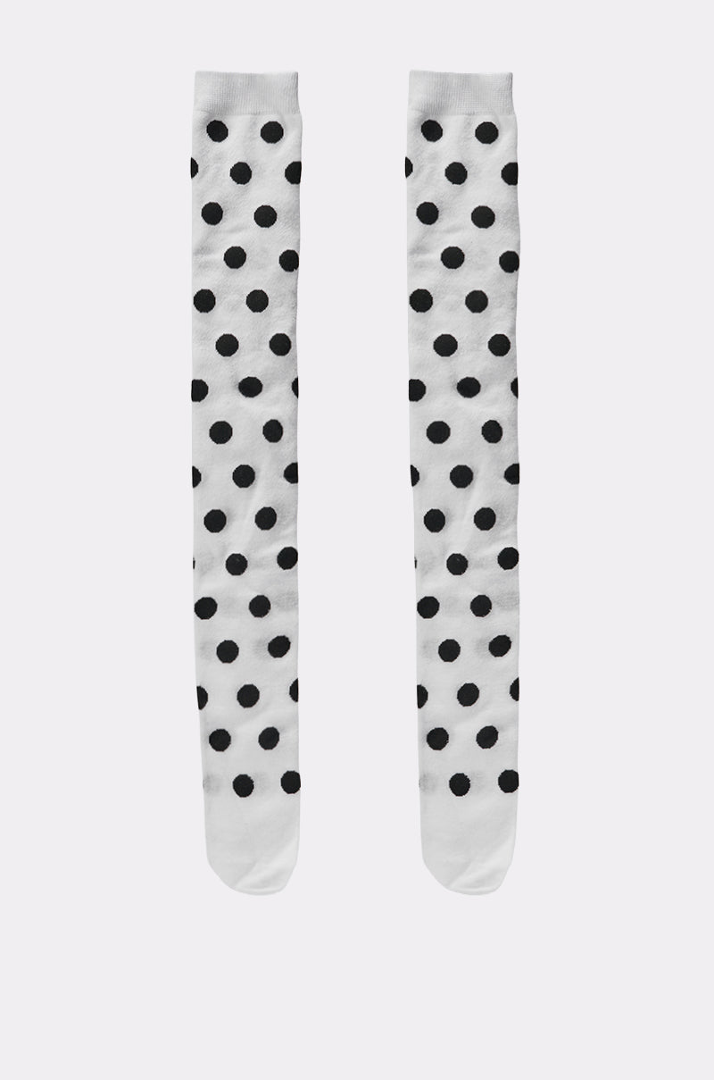 The CALL ME DOTTIE KNEE HIGH SOCKS, a playful white pair with evenly spaced black polka dots, are displayed side by side on a plain light background. 2