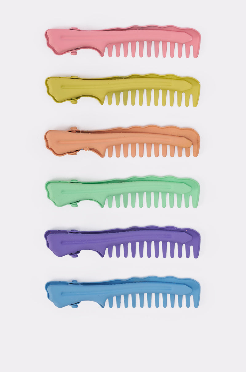 The COMB HERE HAIR CLIP SET includes six large pastel comb-shaped barrettes in pink, yellow, orange, green, purple, and blue, arranged vertically on a white background. 3