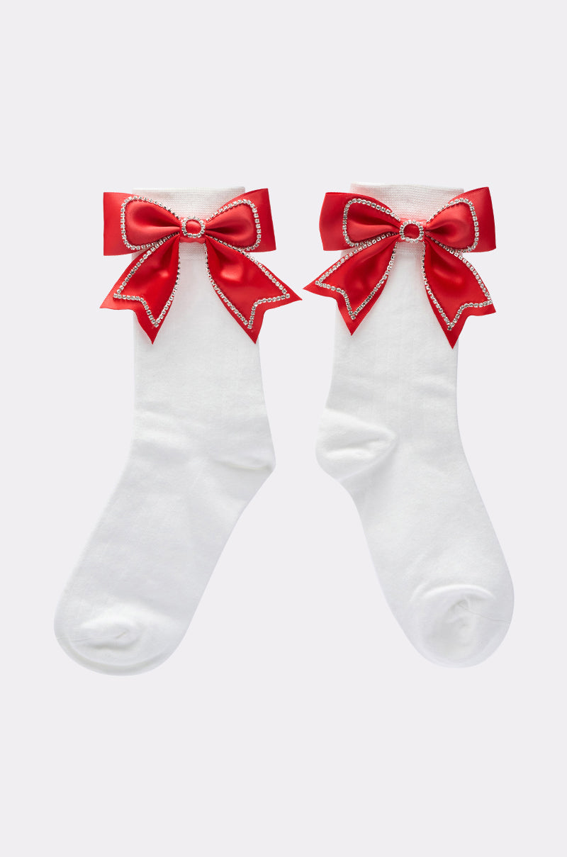 WITH A BOW SOCKS are white crew-length socks, each featuring a large red satin bow with white trim and a small central rhinestone, displayed on a plain light background. 2