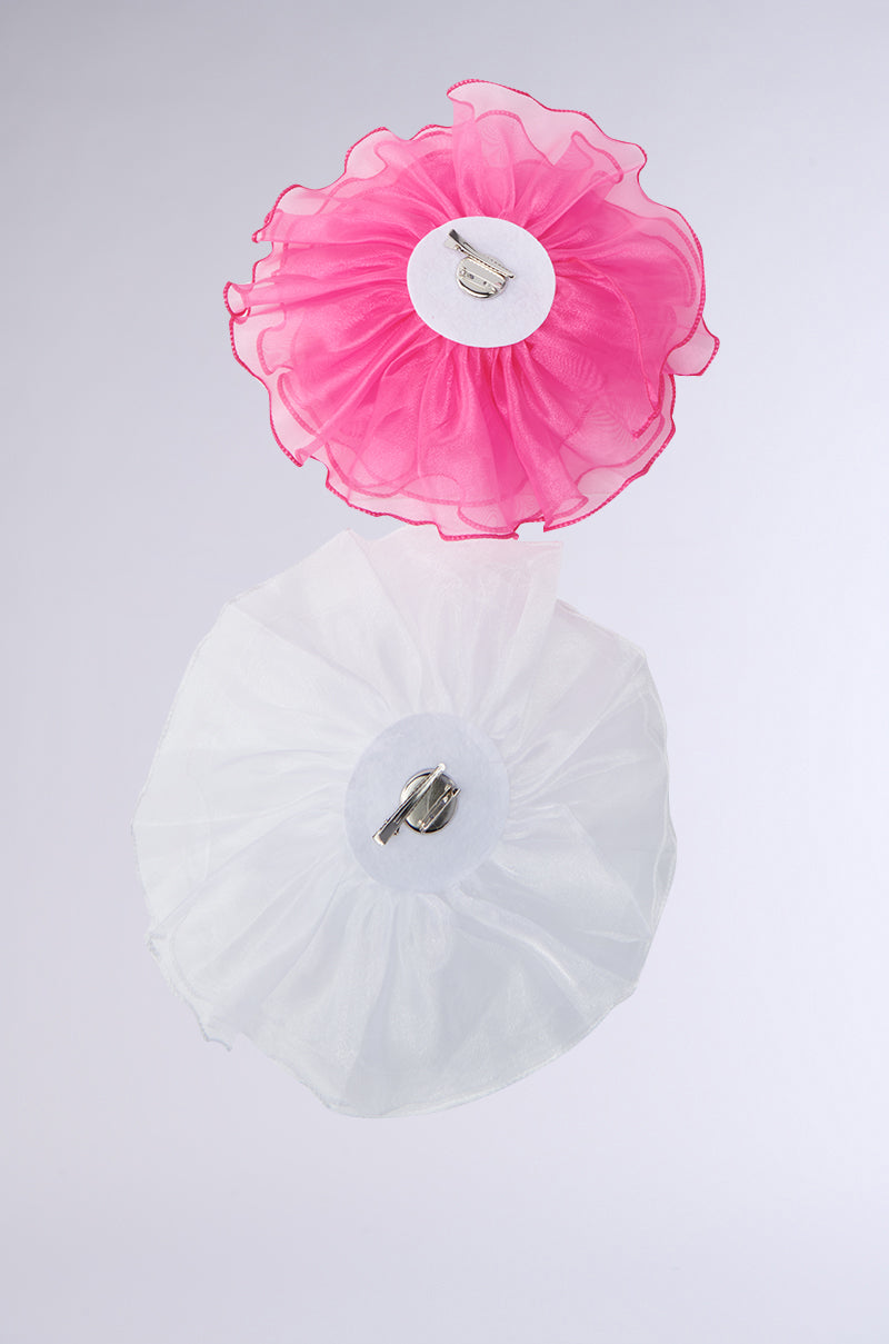 The TIS THE SEASON BROOCH SET showcases two ethereal, circular clips on a plain background: a pink, frilly design and a delicate white piece, both exuding avant-garde romance. 3