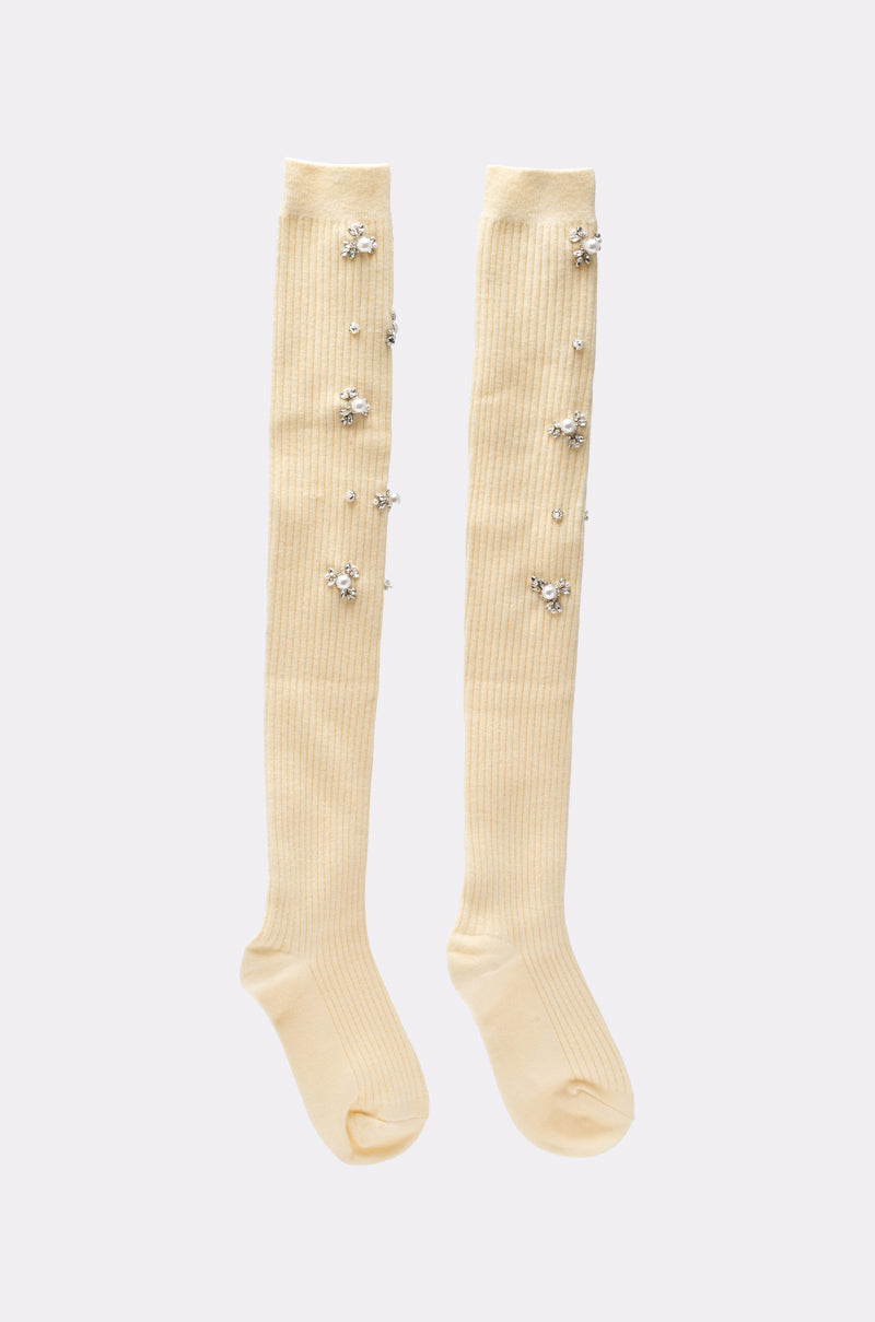 The COCO EMBELLISHED SOCKS IN CREAM are knee-high, ribbed socks adorned with clusters of small, shiny pearls and crystals along the legs. 2
