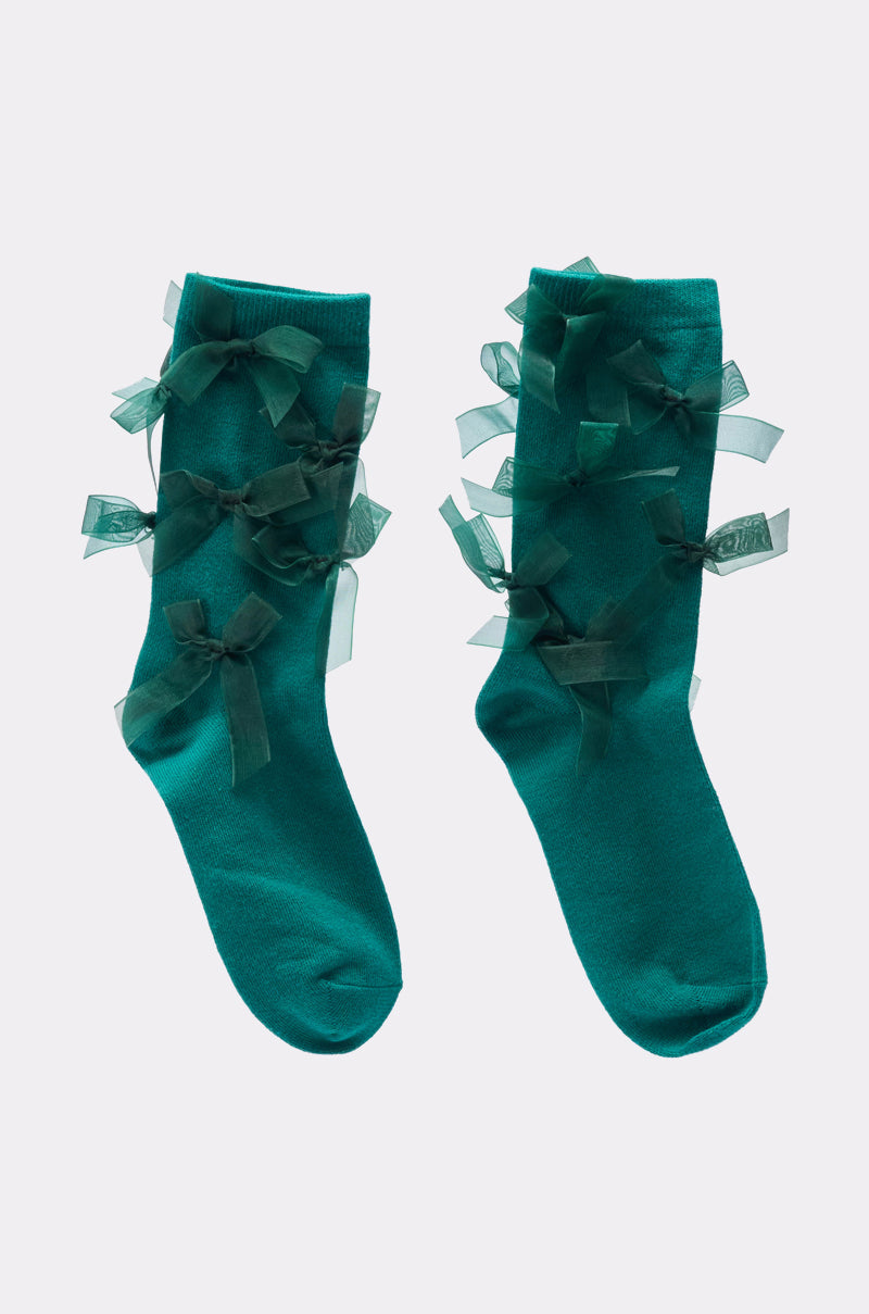 The EMMY BOW SOCKS are teal coquette socks decorated with multiple sheer teal ribbon bows along the sides, displayed on a light gray background. 3