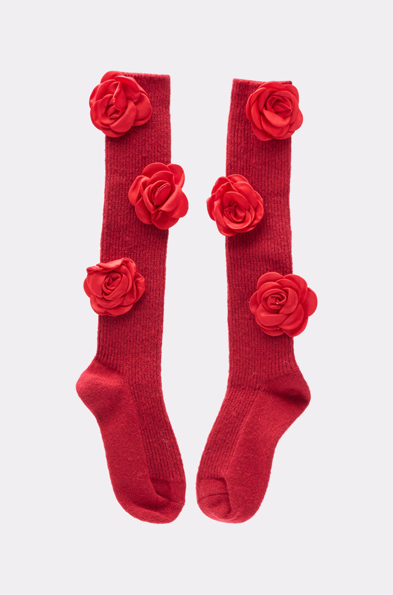 ROSIE SOCKS: These knee-high red socks feature bold, three-dimensional rosette appliques on the front, adding a unique floral touch. Photographed side by side against a plain light background. 1