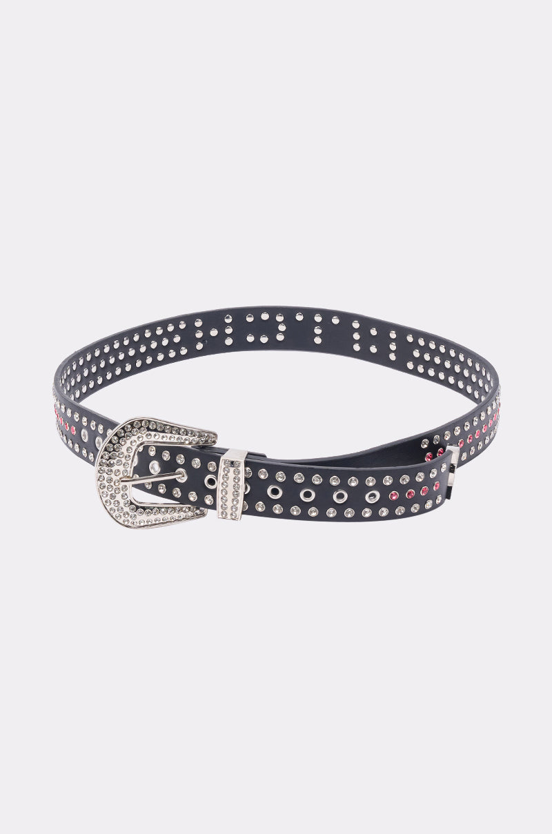 The "I AM THAT BELT" is a faux leather belt featuring a large western buckle and adorned with small silver and red studs along its length, shown against a plain white background. 7