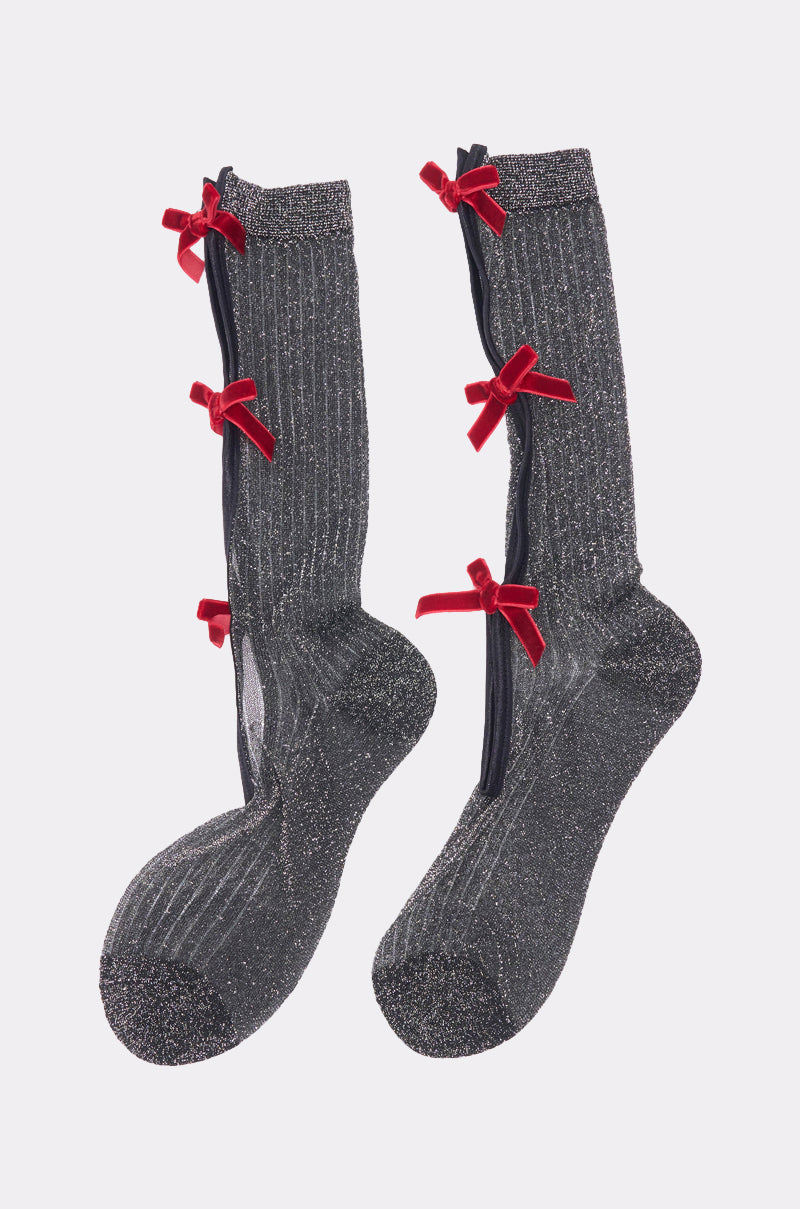 TIS THE SEASON BOW SOCKS are sparkling gray knee-highs with black side zippers and three small red velvet bows. Featuring a ribbed texture and metallic sheen, they’re the perfect festive, playful addition to any outfit. 2