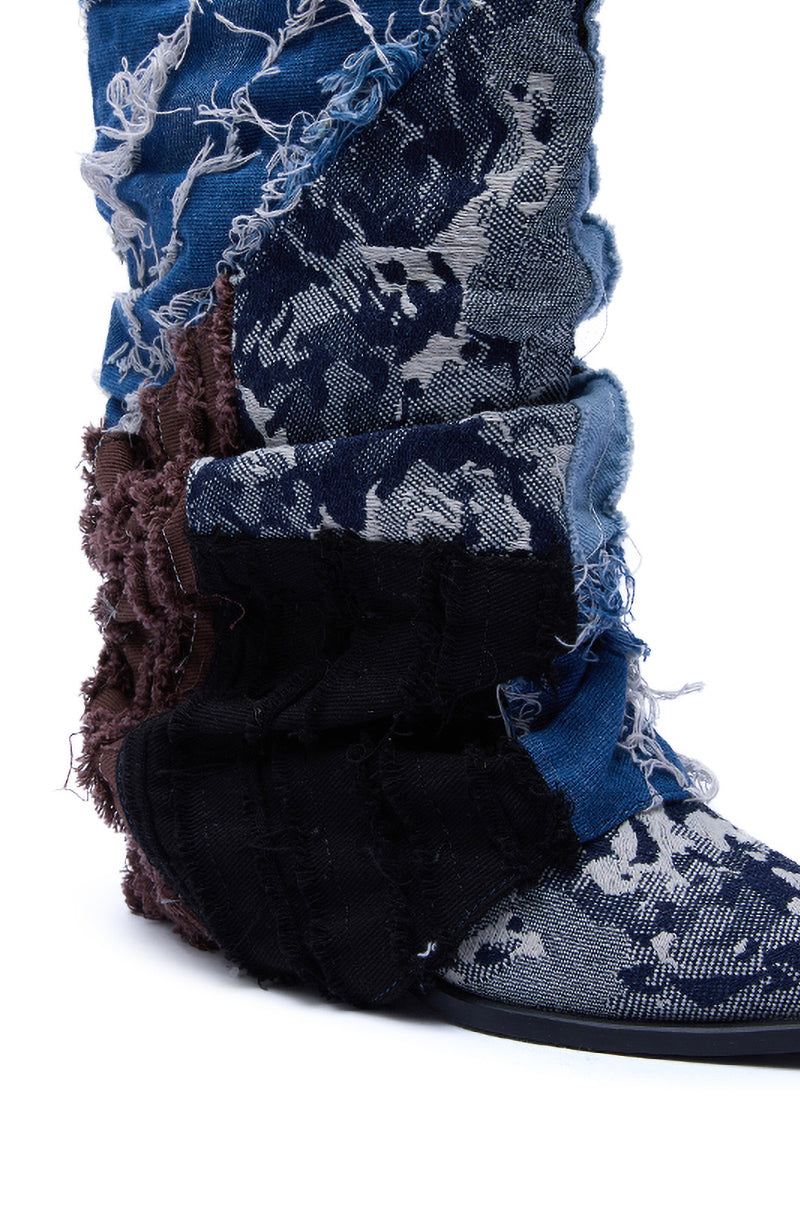 The AZALEA WANG GABRYLE MULTI MATERIAL WESTERN BOOTIE showcases a close-up of layered, frayed denim patches in blue, black, and brown with a distressed patchwork design and a stylish chunky heel.