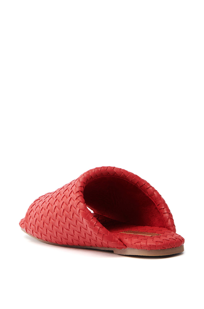 The AKIRA GAIA Red Braided Flat Slip-On Sandal is a faux leather sandal featuring a textured pattern and open toe design, seen from a low back angle. This stylish slip-on offers a flat sole, perfectly blending comfort with fashion.