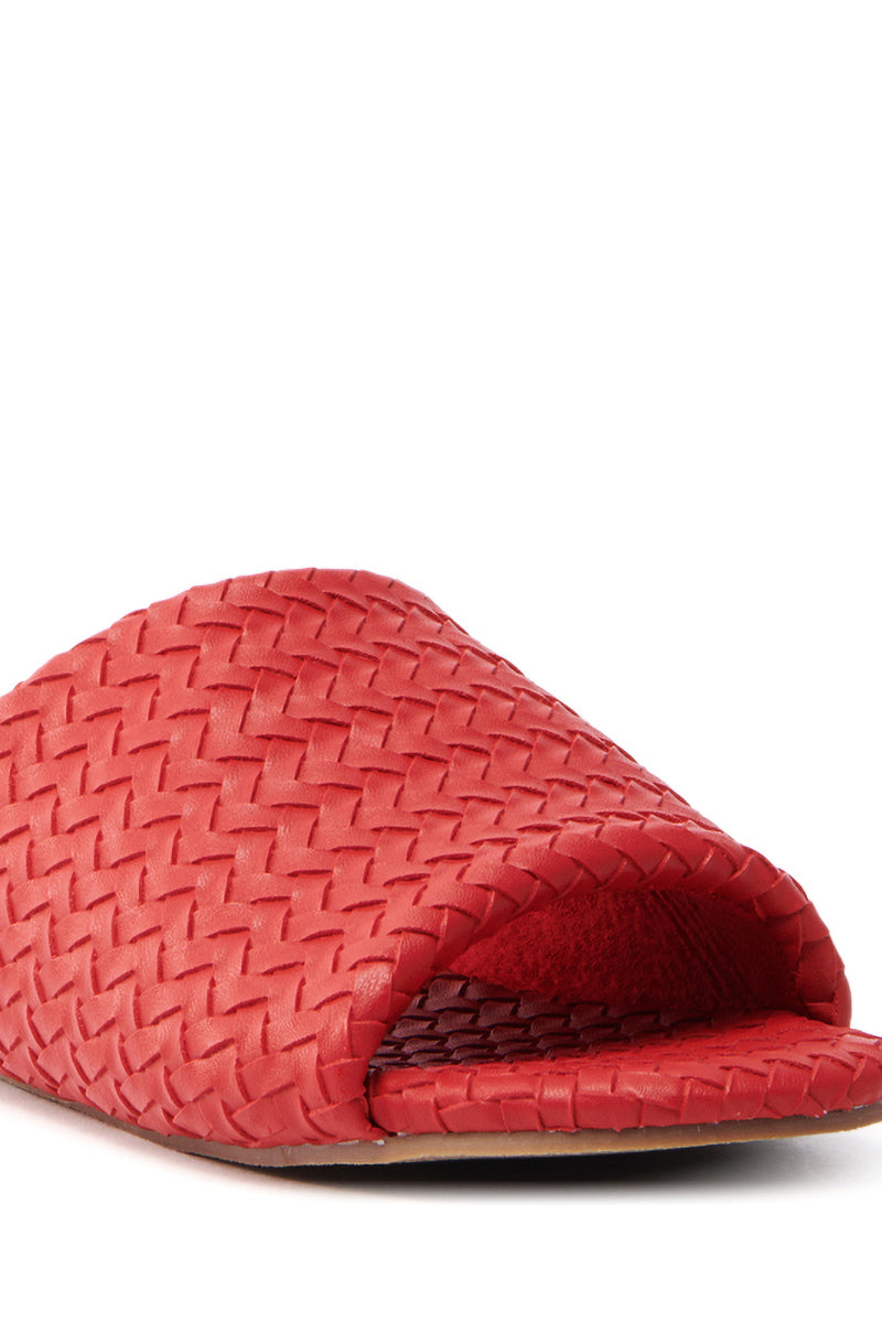 The AKIRA Gaia Red Braided Flat Slip-On Sandal is showcased in cherry red with an open toe and textured pattern, offering a faux leather design that combines modern style and cozy comfort.