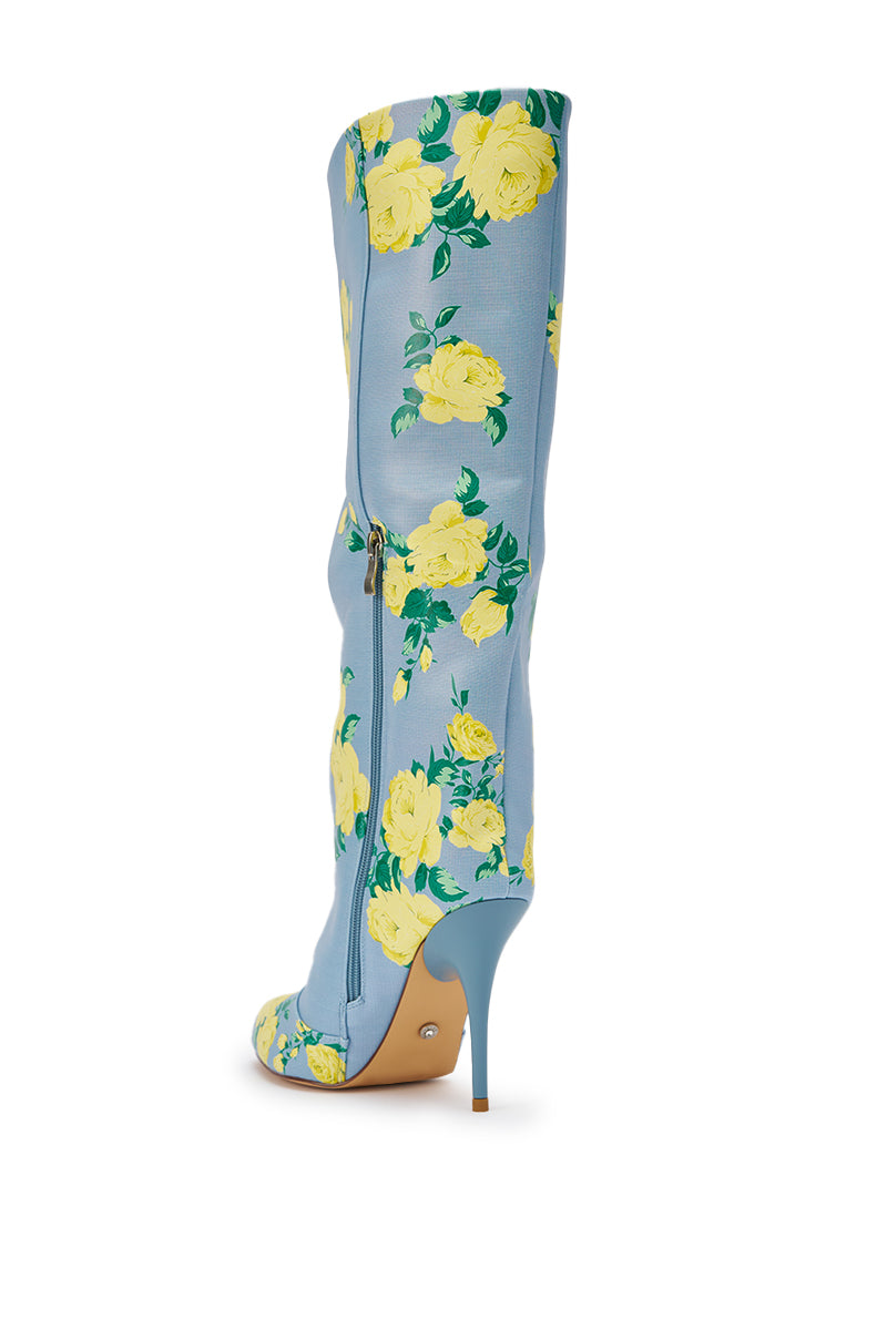 The AKIRA GOLD GARLAND BLUE FLORAL BOOT is a tall, pointed-toe knee-high stiletto with a blue background, yellow rose print, high heel, and side zipper. 7