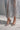 Wearing the AZALEA WANG GARNET SILVER PUMP, a person in a sheer, silver sequin dress stands on a light floor, with only their lower legs and feet visible.