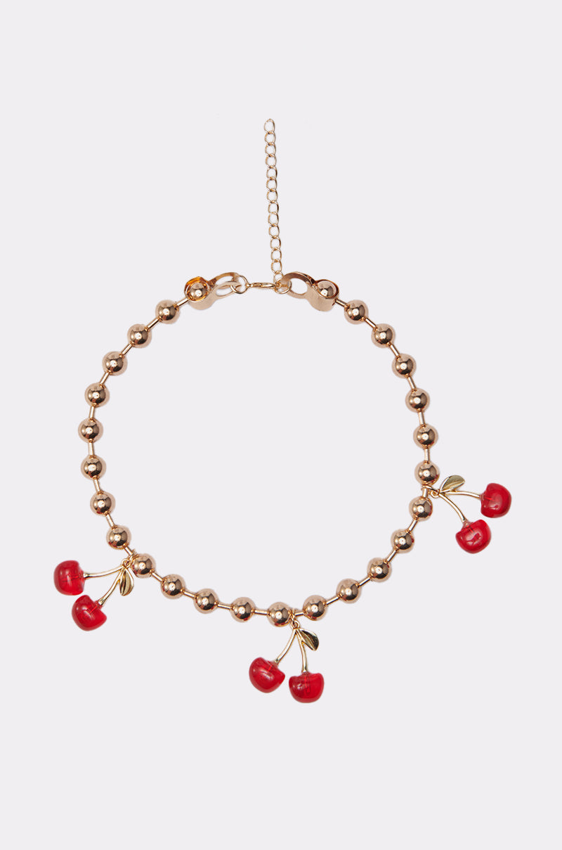 The POP MINE NECKLACE is a gold-tone chain with four cherry-shaped charms featuring green leaves, evenly spaced around the band, and finished with an adjustable clasp. 0