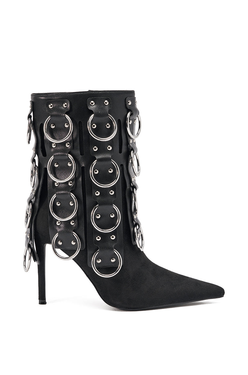 The AKIRA GOLD GERANIUM BLACK PIERCING STILETTO BOOTIE is a black pointed-toe ankle boot with striking silver rings and buckles on both sides, creating a bold, edgy statement.