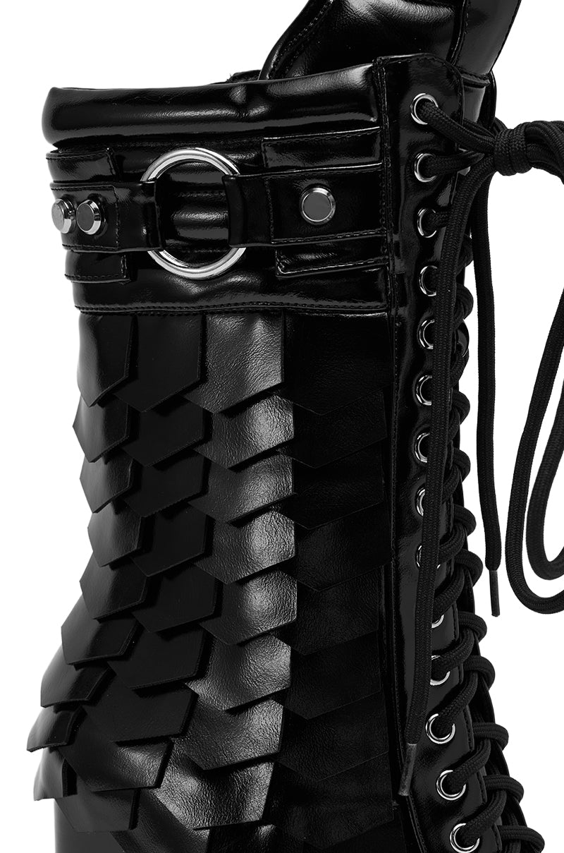 Close-up of the AZALEA WANG GERNOT BLACK LACE UP SCALED PLATFORM BOOTIE, featuring shiny black faux leather, layered scales, metallic eyelets, decorative rings, and bold stitching for a striking and textured look.