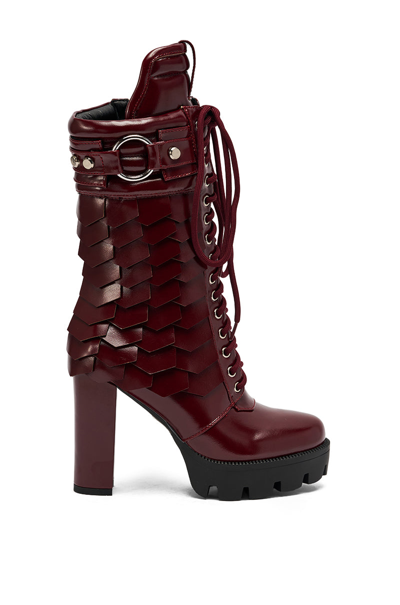 The AZALEA WANG GERNOT BURGUNDY LACE UP SCALED PLATFORM BOOTIE features shiny dark red faux leather, a chunky sole, lace-up front, decorative belt with metal ring, and layered scale-style side details. 3