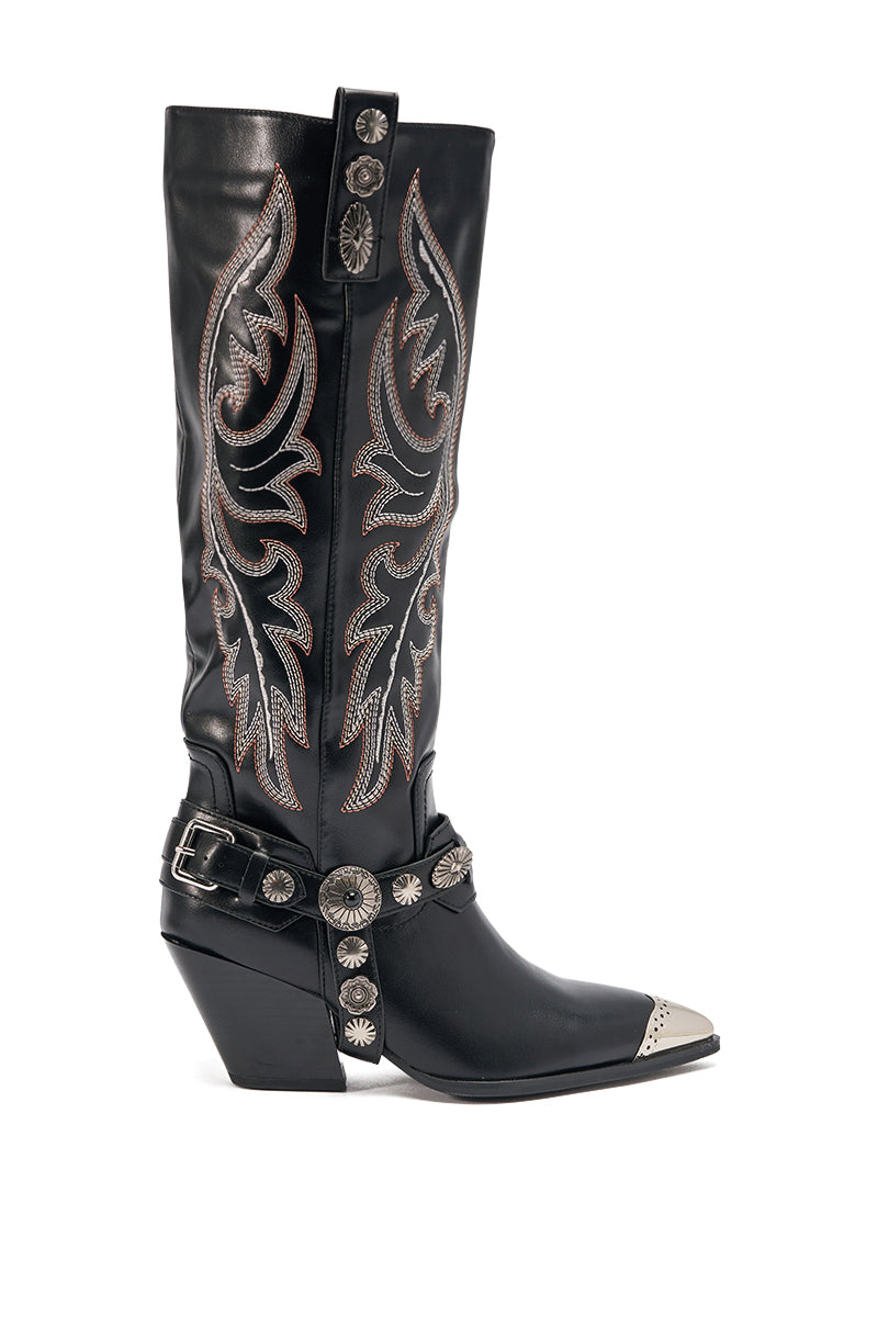 The AZALEA WANG GERVASE BLACK PU SILVER HARDWARE WESTERN BOOT is a knee-high faux leather boot with silver stitching, metal toe cap, harness strap with silver conchos, and ornate western designs on the shaft. 3