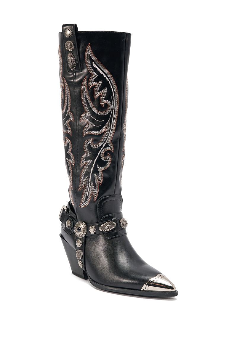 The AZALEA WANG GERVASE BLACK PU SILVER HARDWARE WESTERN BOOT is a knee-high black boot with silver stitching, a metal toe cap, engraved accents, chunky angled heel, and a harness with silver conchos and ornate western patterns. 4