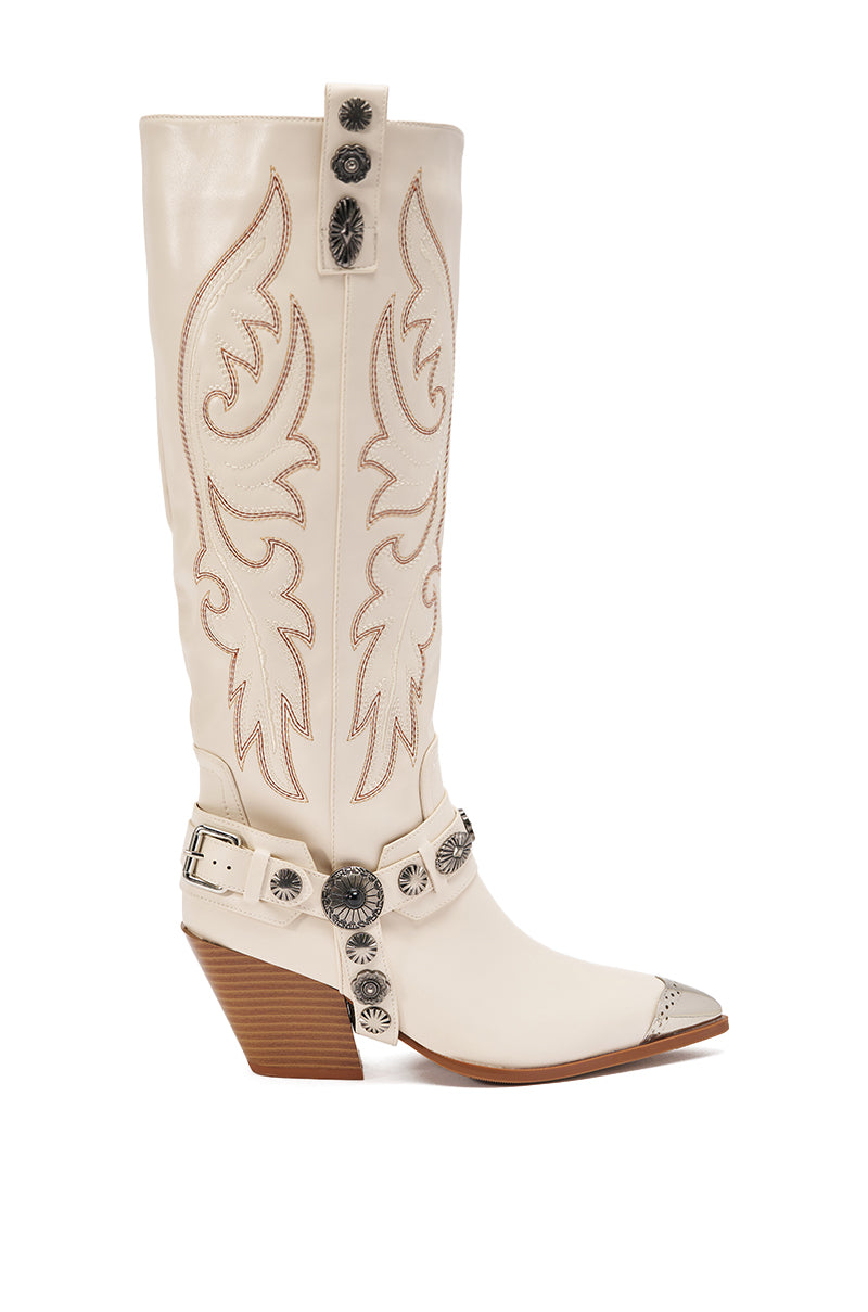 The AZALEA WANG GERVASE Bone PU Silver Hardware Western Boot features tall white faux leather, tan stitching, silver studs and conchos, a pointed toe, angled wooden heel, and harness-style straps on the ankle and shaft. 4