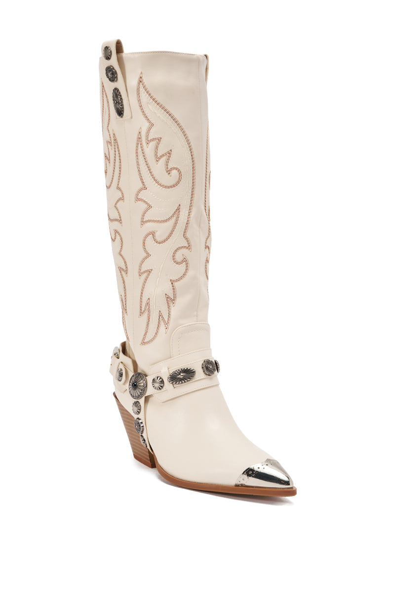 The AZALEA WANG GERVASE BONE PU SILVER HARDWARE WESTERN BOOT is a tall, cream-colored knee-high boot featuring intricate tan stitching, a pointed toe with silver tip, decorative metal accents, and a slanted wooden heel. 5